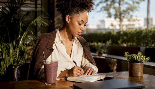 Young woman writing notes at glass desk in office