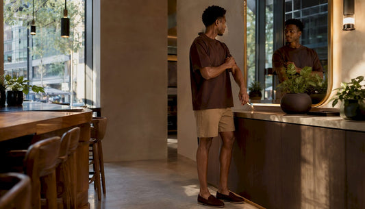 Man styling boxy-fit shirt in modern apartment