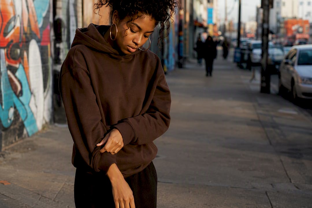 Model adjusting hoodie sleeve outdoors