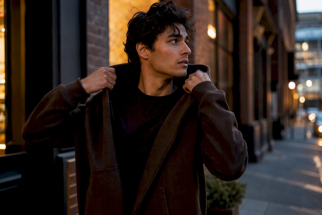 Person putting on hoodie outdoors side view